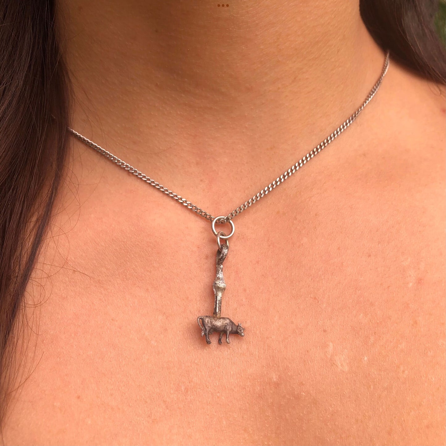 Anhänger Kuh aus Silber am Hals getragen.
