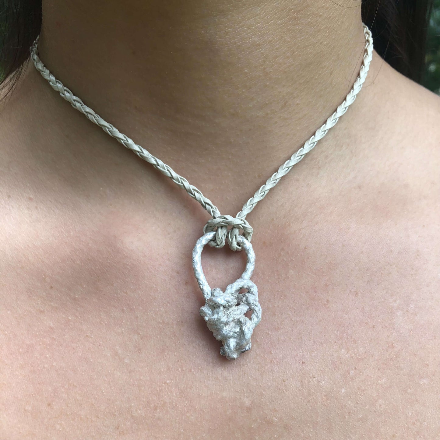 Kettenanhänger als Knoten getragen an einem Lederhalsband am Hals.