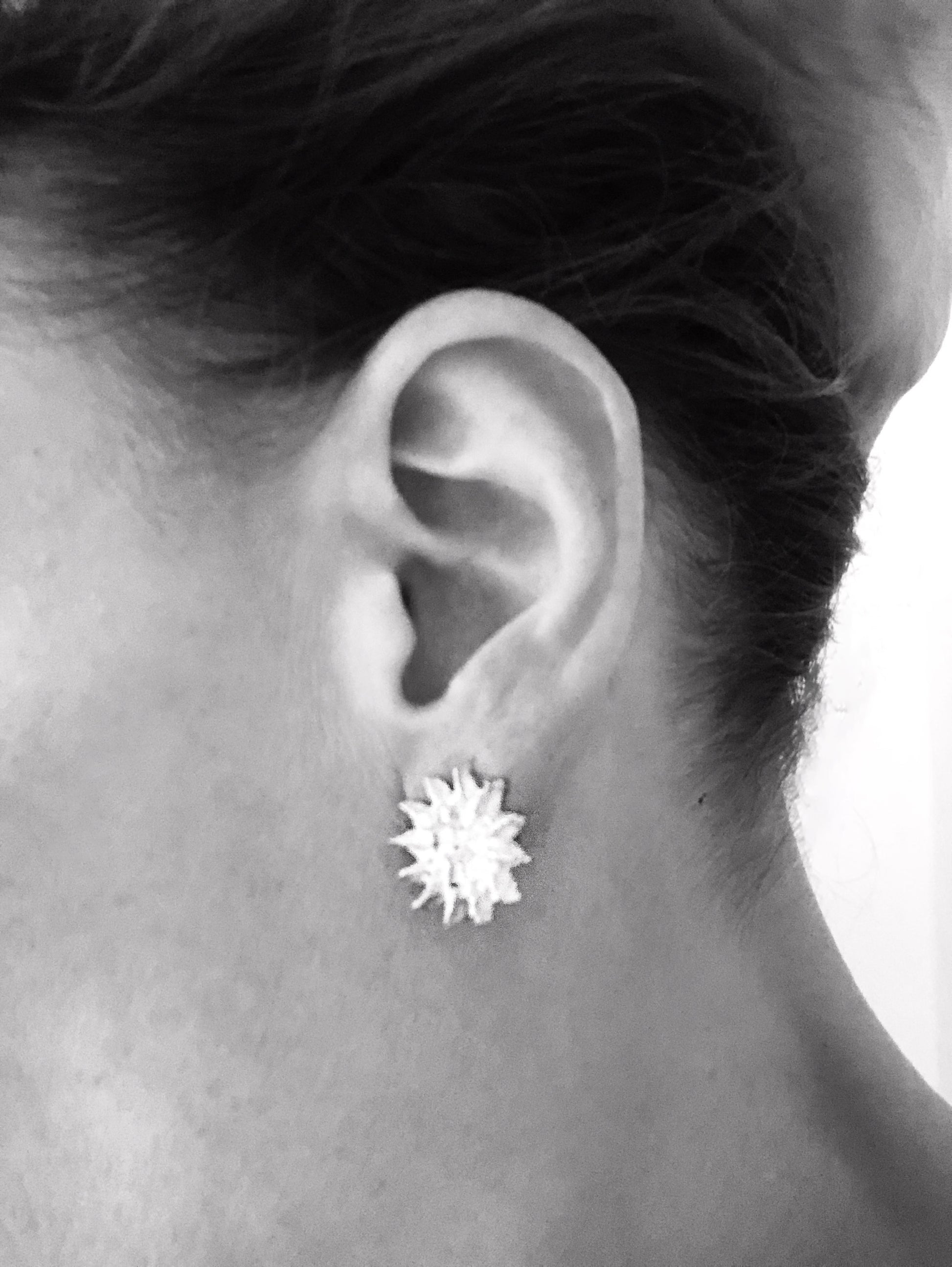 Frau trägt die filigranen Silber-Ohrstecker „Himmelszauber“ mit Sonne, Mond und Sternen, seitliche Nahaufnahme.