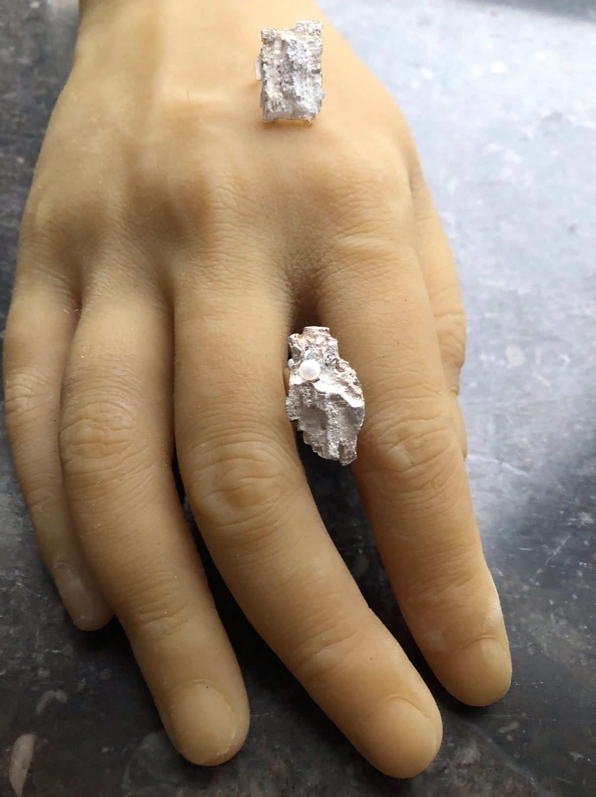 Organische Silberohrstecker auf einer Hand liegend.