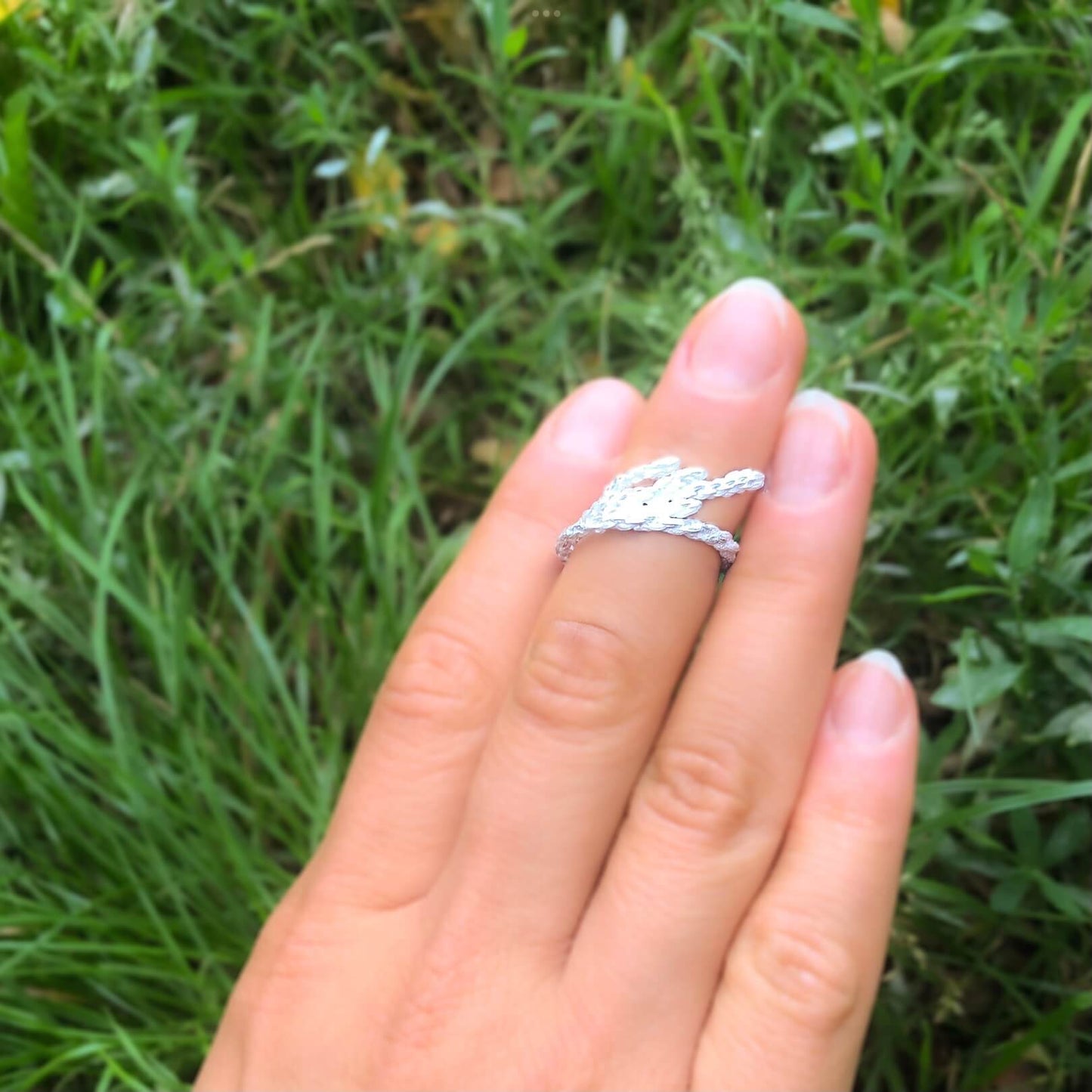 Eine Hand trägt einen zarten Astsilberring am oberen Finger.