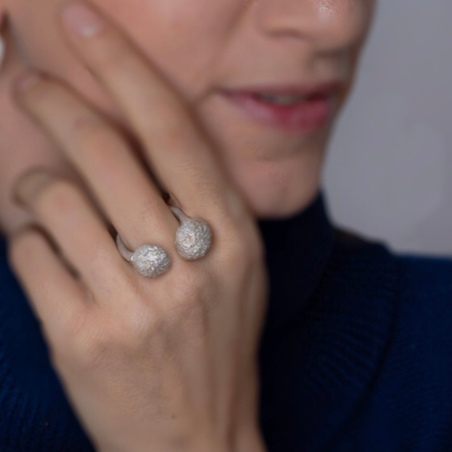 Offener Silberring Blütenstand mit zwei organischen Kügelchen, elegant am Finger getragen, betont die Verbindung von Natur und Handwerk.
