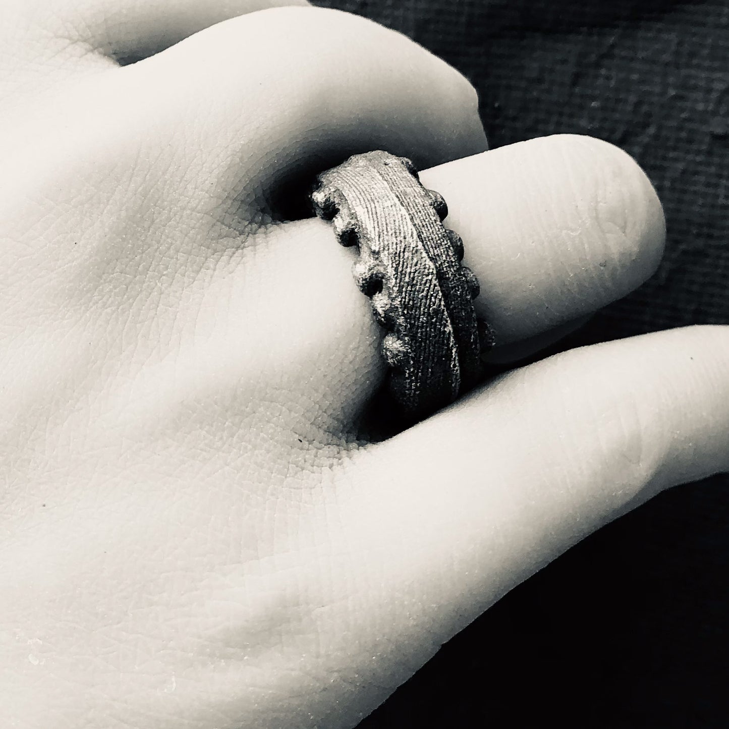 Schwarz-weißes Bild einer Hand, die den geschwärzten Silberring „Ein Ring wie das Meer“ trägt, betont die natürliche Kraft und Eleganz des Schmuckstücks.