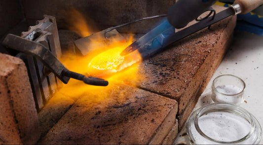 Goldschmiedearbeiten. Silber wird gerade mit einer Flamme geschmolzen. Bild für den Blogartikel Goldschmied versus Schmuckdesignerin