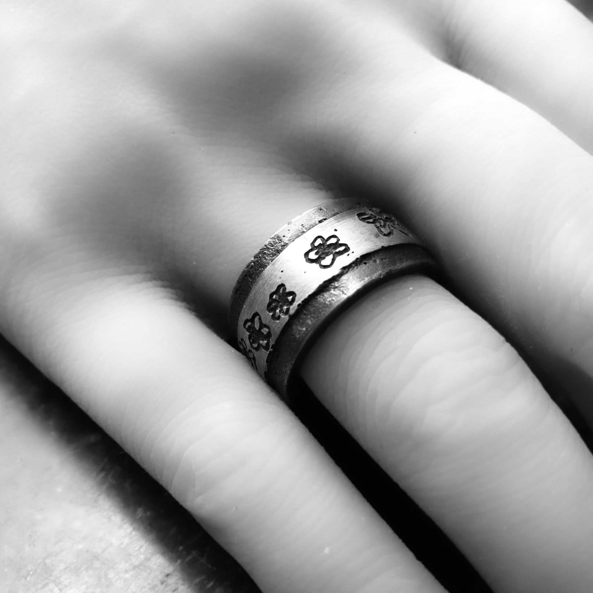 Silberring mit Blümchen an einer Hand fotografiert.