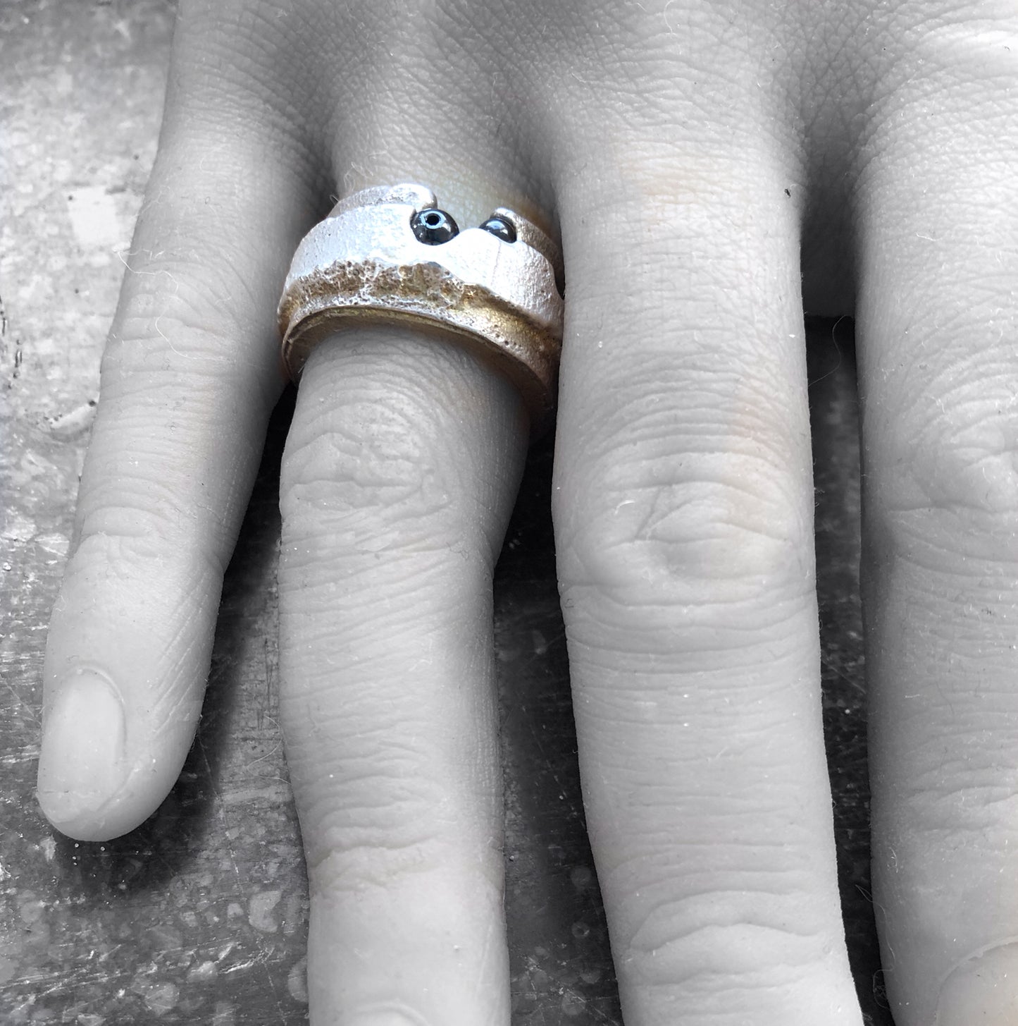 Handgefertigter breiter Silberring als Statement-Schmuckstück, getragen vor einem kontrastreichen Schwarz-Weiß-Porträt.