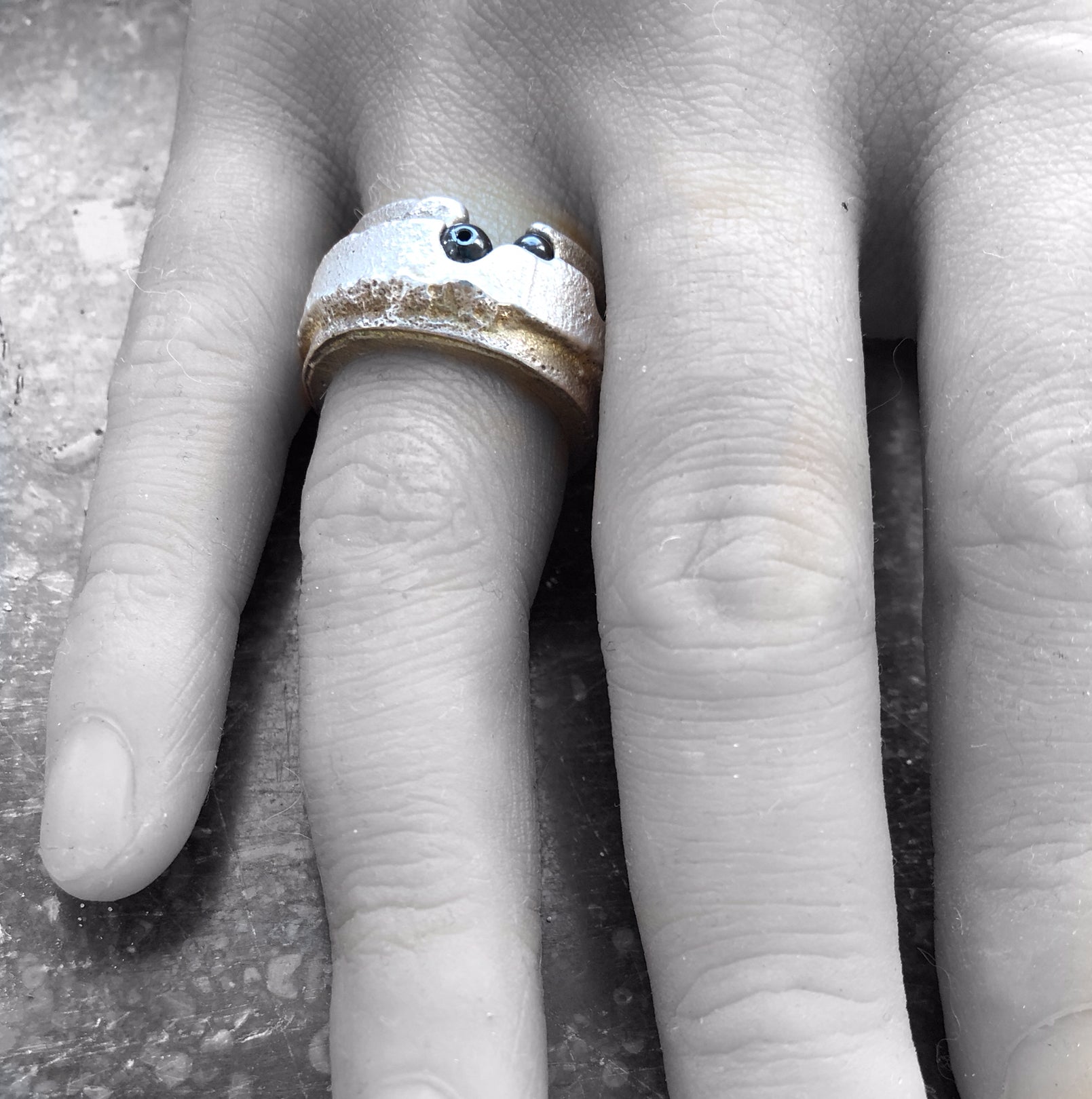 Handgefertigter breiter Silberring als Statement-Schmuckstück, getragen vor einem kontrastreichen Schwarz-Weiß-Porträt.