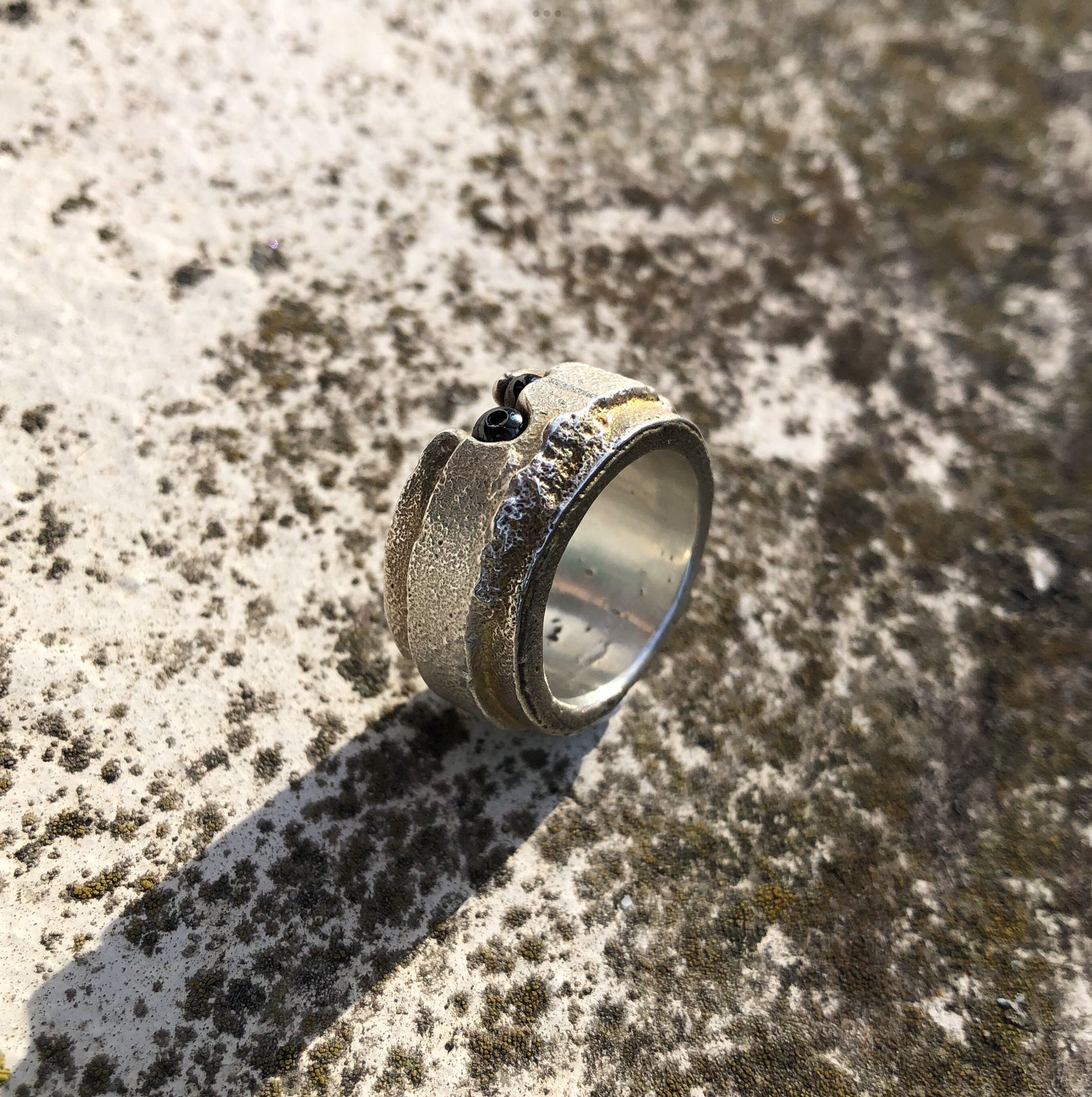 Massiver Silberring auf beigem Untergrund mit zarten Moosen und Flechten, handgefertigt von Ricarda Enderweit in Bielefeld.