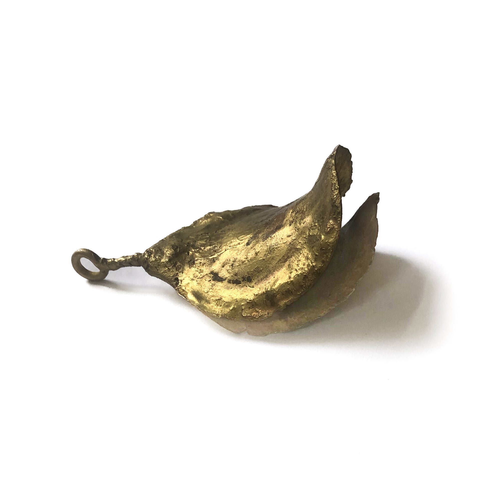 Seitenansicht des handgefertigten Messingschotenanhängers, zeigt die filigrane Struktur und natürliche Form.