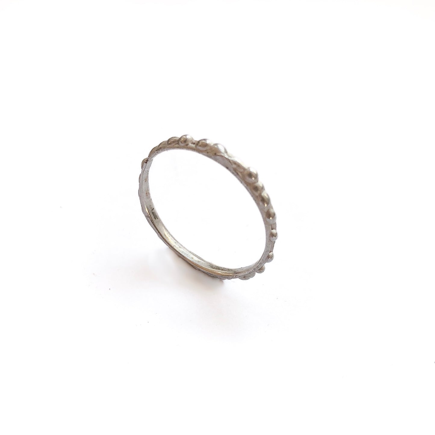 Ein schmaler, stehender 935er Silberring mit einer feinen, verlaufenden Kügelchen-Struktur auf weißem Hintergrund.