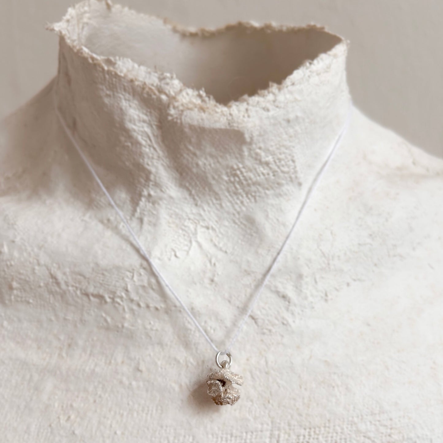 Detailaufnahme eines geöffneten Zypressenzapfen-Anhängers aus Silber an einer Büste – zeigt die feine organische Struktur und plastische Tiefe des Designs