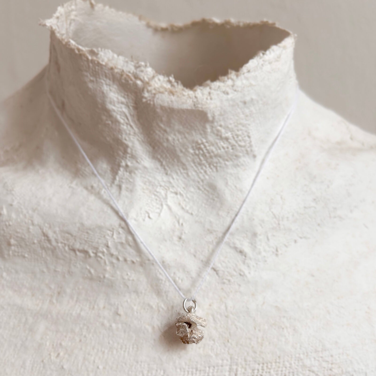 Detailaufnahme eines geöffneten Zypressenzapfen-Anhängers aus Silber an einer Büste – zeigt die feine organische Struktur und plastische Tiefe des Designs