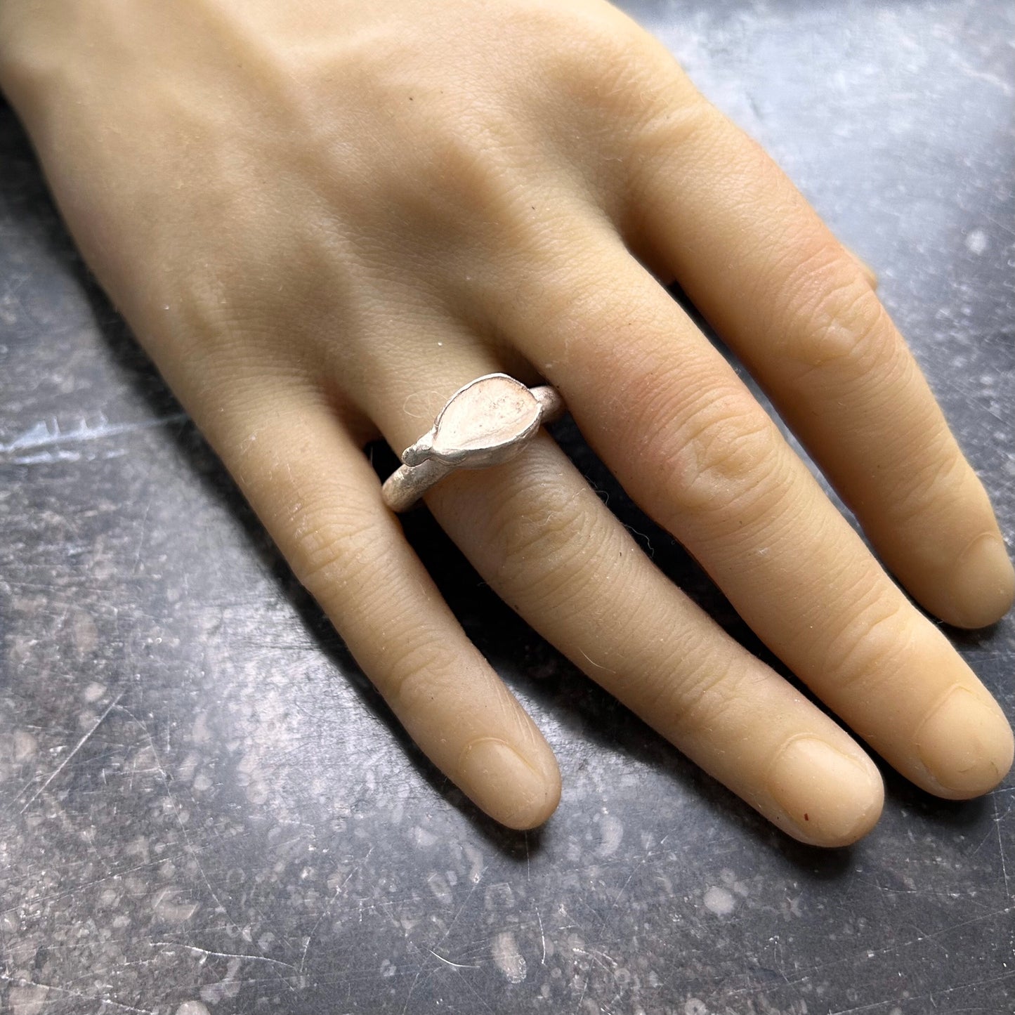 Nahaufnahme eines breiten Silberring-Unikats an der Hand eines Menschen, die die angenehme Passform und Präsenz unterstreicht.