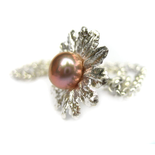 Seitliche Abbildung des Armbandanhängers in Blütenform und eine großen rosafarbenen Perle.